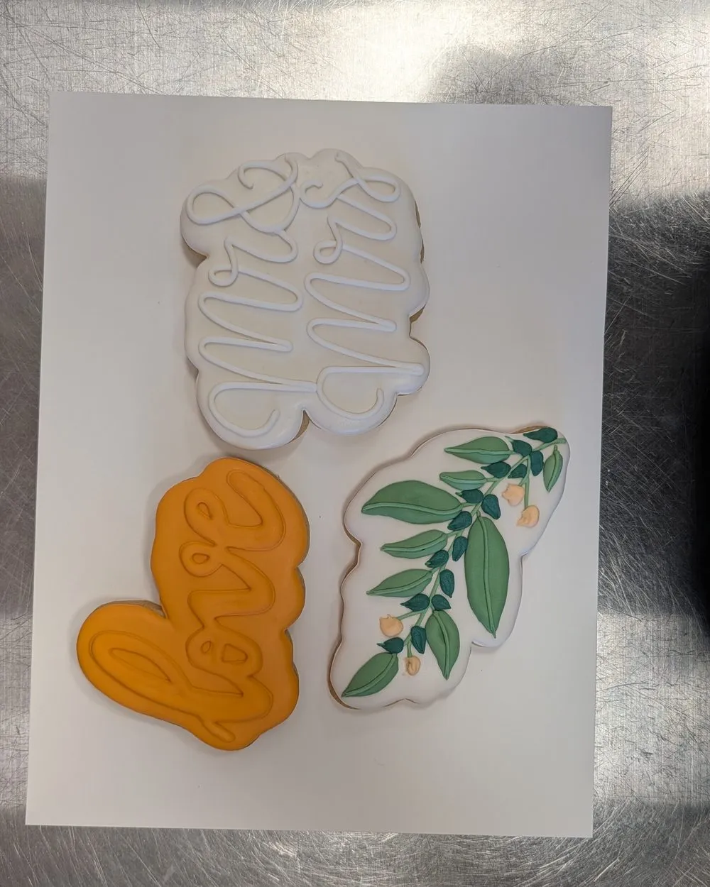 Iced sugar cookies with a script love message, an orange heart and a leafy branch
