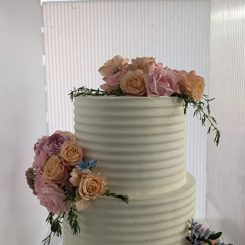Two-tier ribbed buttercream cake with peach and pink roses